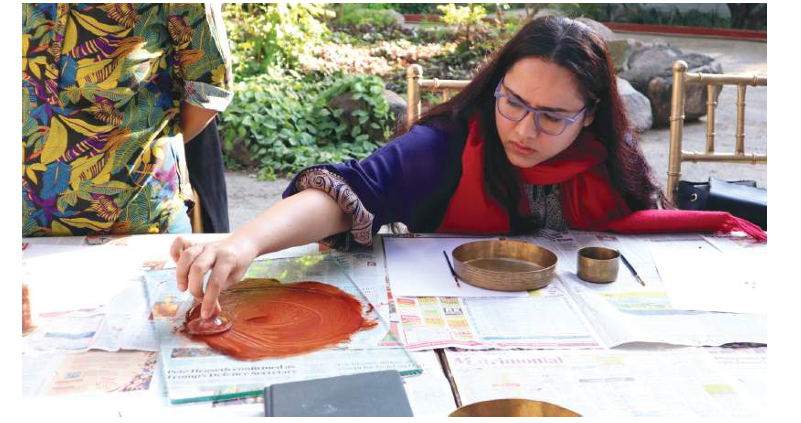 Artist working on a painting at an outdoor table